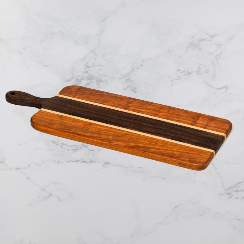 Wood serving board with a handle on a marble surface.