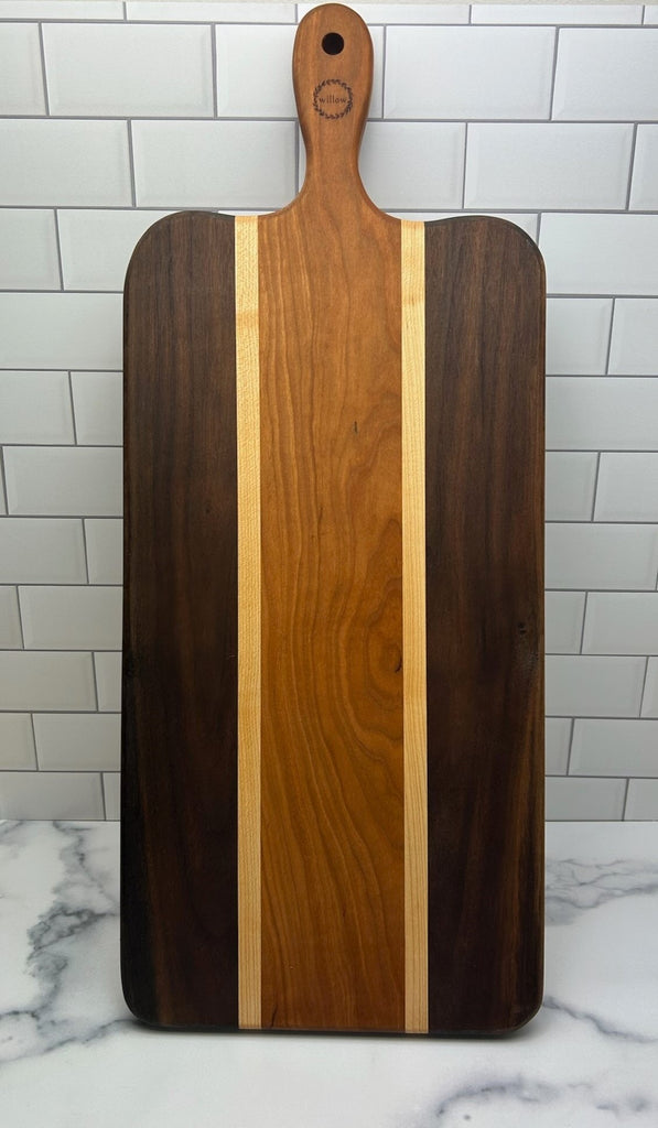 Handmade Wood Charcuterie Board with a handle on a marble surface with a tiled wall background