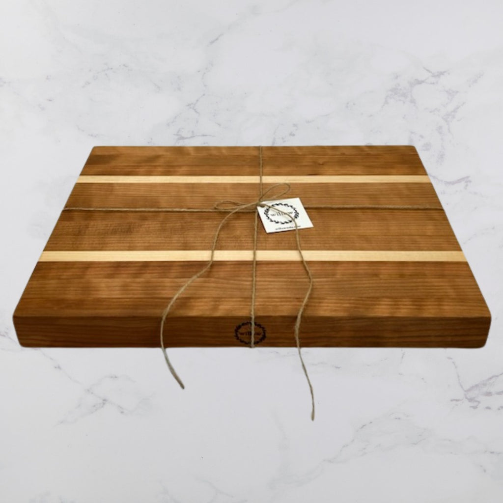 Handmade wooden cutting board with a string tied around it on a marble surface.