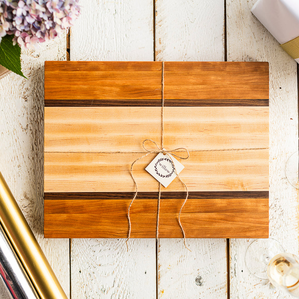 Willow cutting board staged as a wedding gift on old barn wood with hydrangea, champagne and wedding gift.