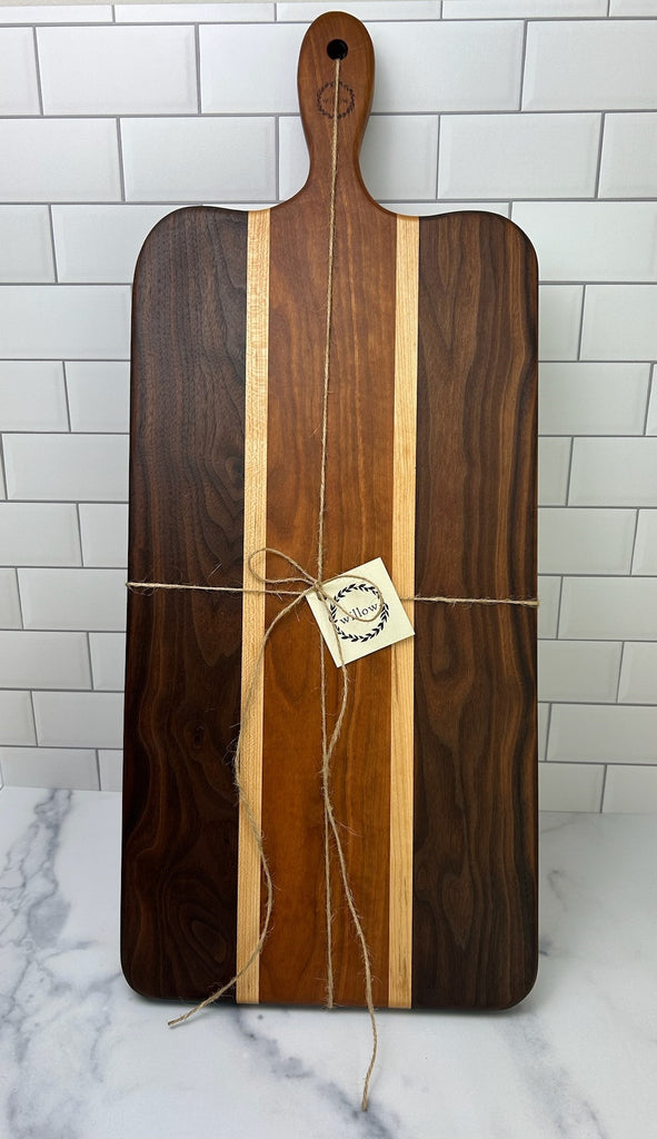 Wooden cutting board with twine and a Willow Boards card on a marble surface with tiled wall background
