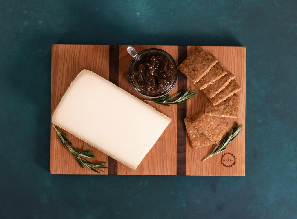 Cheese board with cheese, crackers, jam and rosemary.