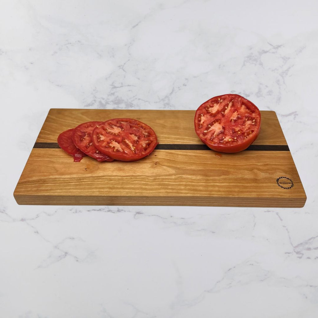 Wood cheese board with fresh sliced tomatoes on a marble surface
