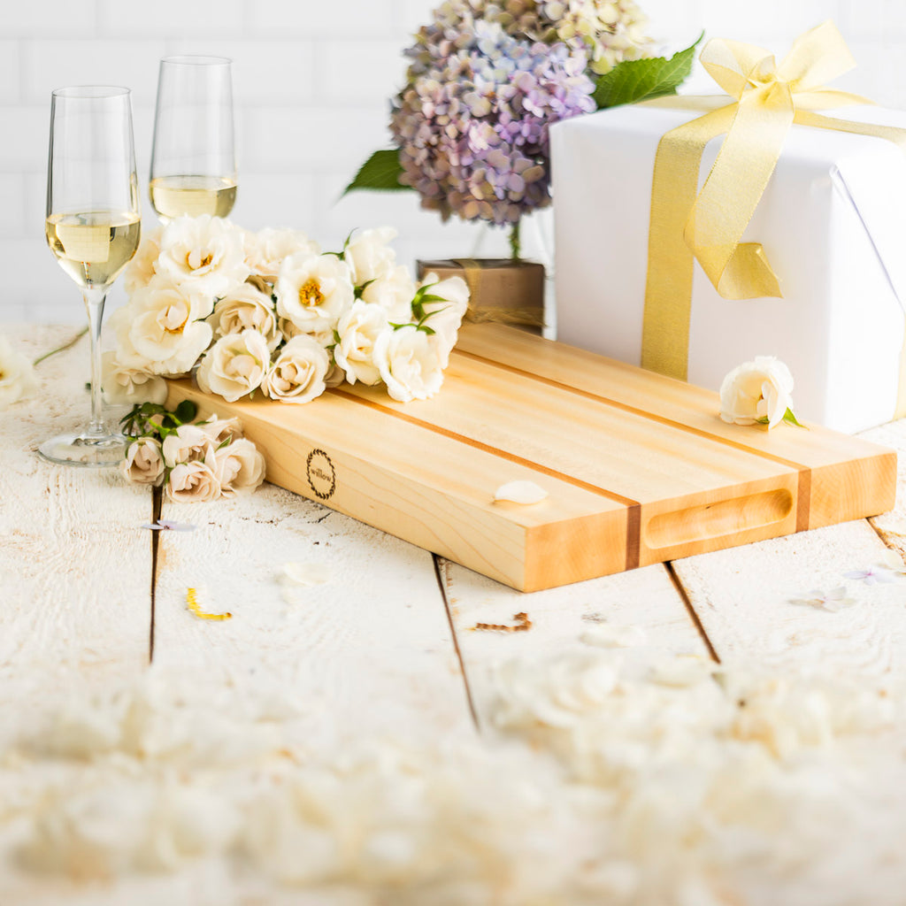Vermont Sugar Maple Wood Cutting Board staged as the perfect wedding gift with roses, champagne, hydrangea and wedding gifts. 
