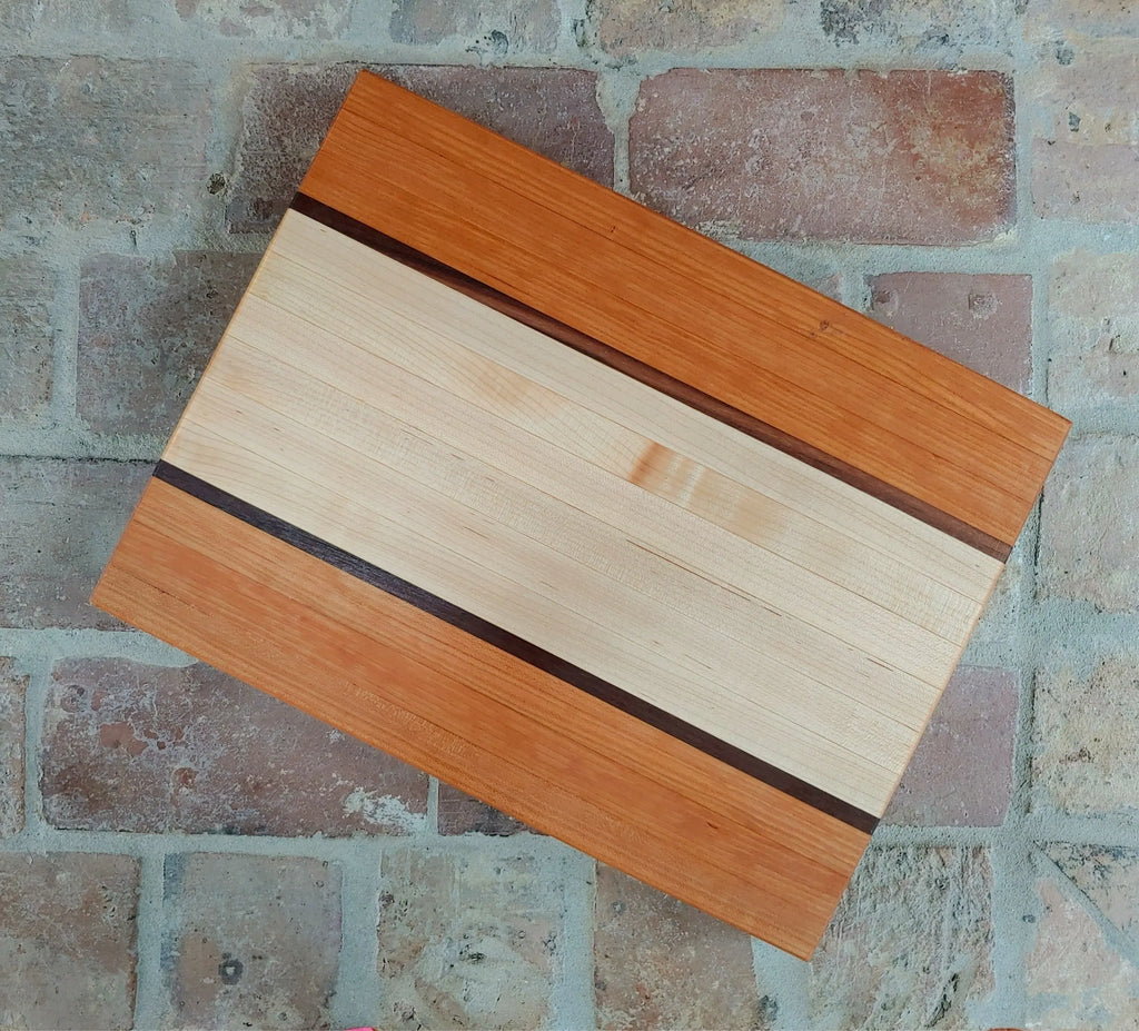 Natural wood cutting board made of cherry and Vermont maple on old brick surface.